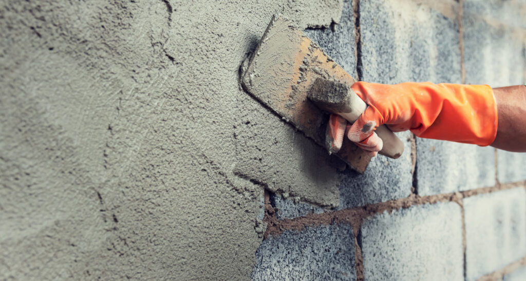 close up hand worker plastering cement on wall for building hous