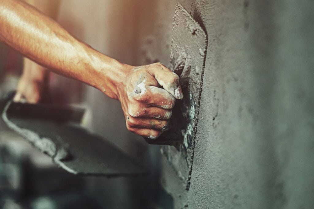 closeup hand worker plastering cement wall building house