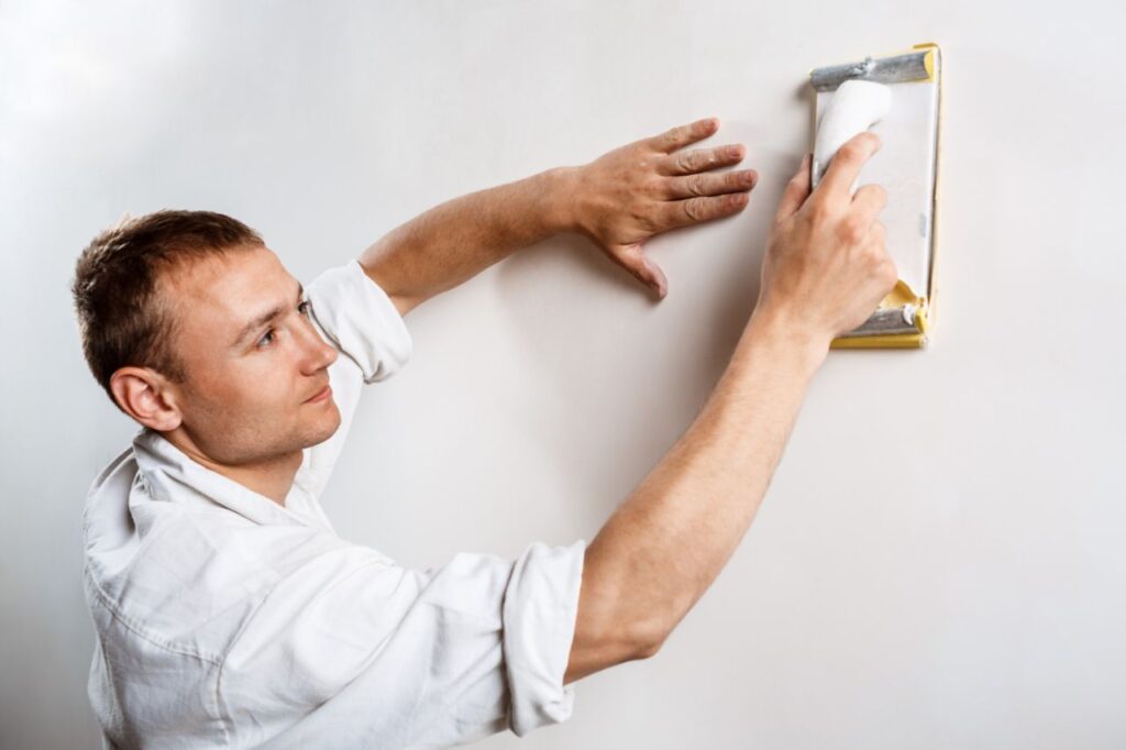 worker grinding white wall with sandpaper (2)