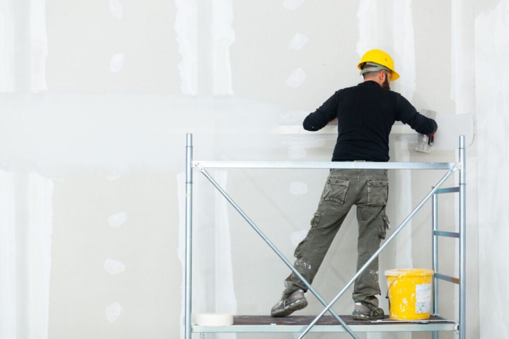 worker plastering gypsum board wall