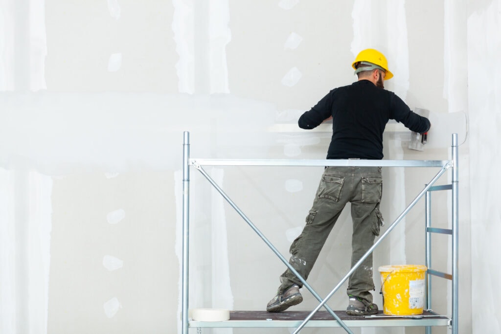 worker plastering gypsum board wall.